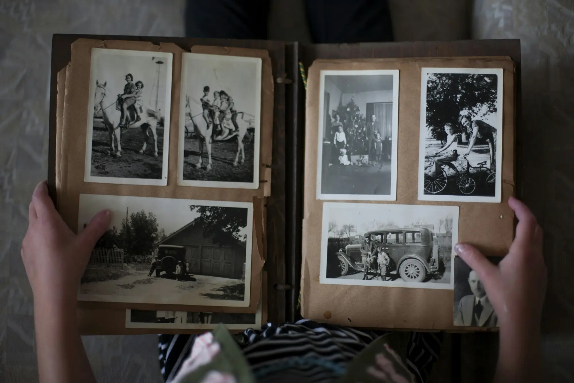 Hands turning the pages of an album of black-and-white family photographs