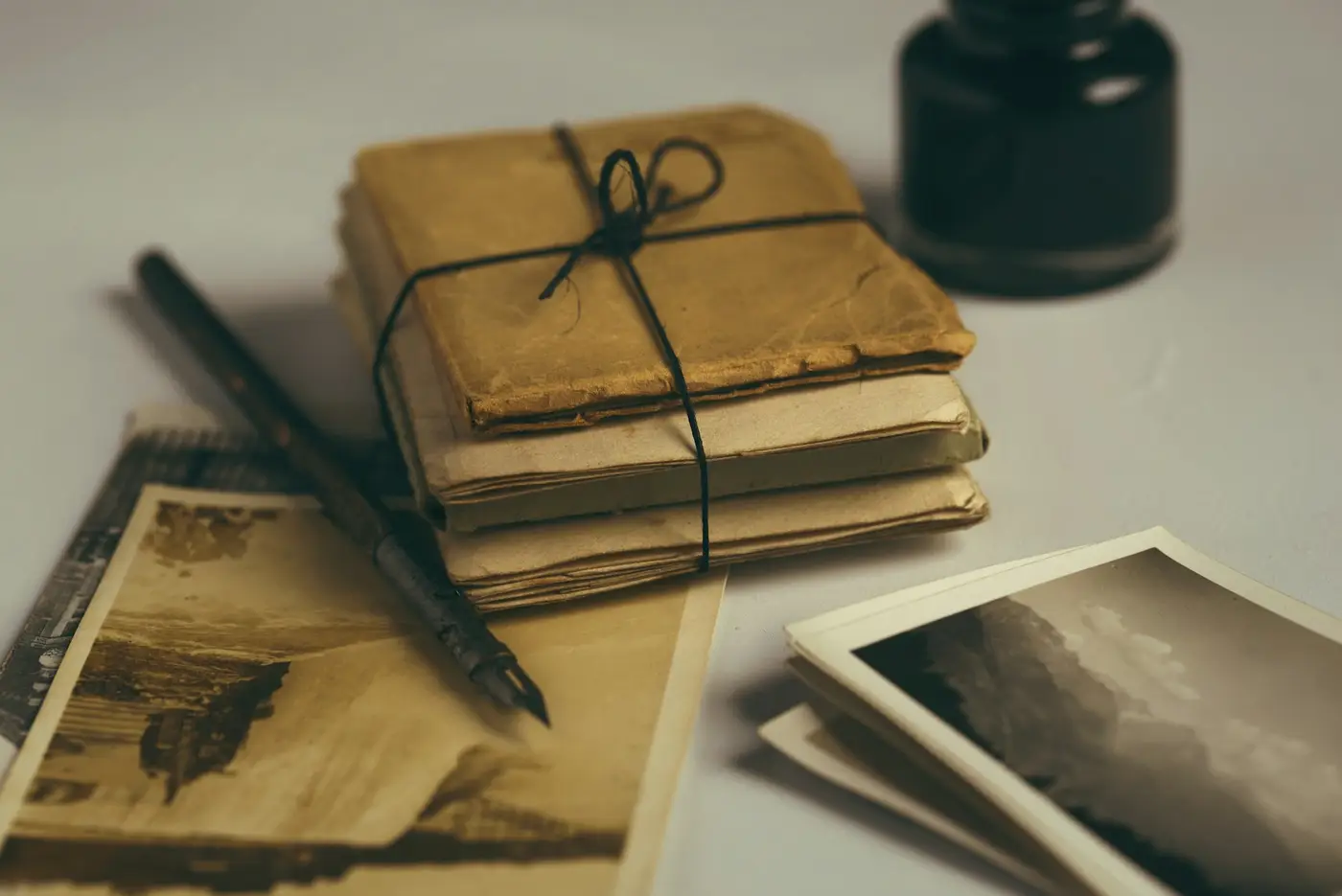 A bundle of old letters tied with string, a pen and old photographs